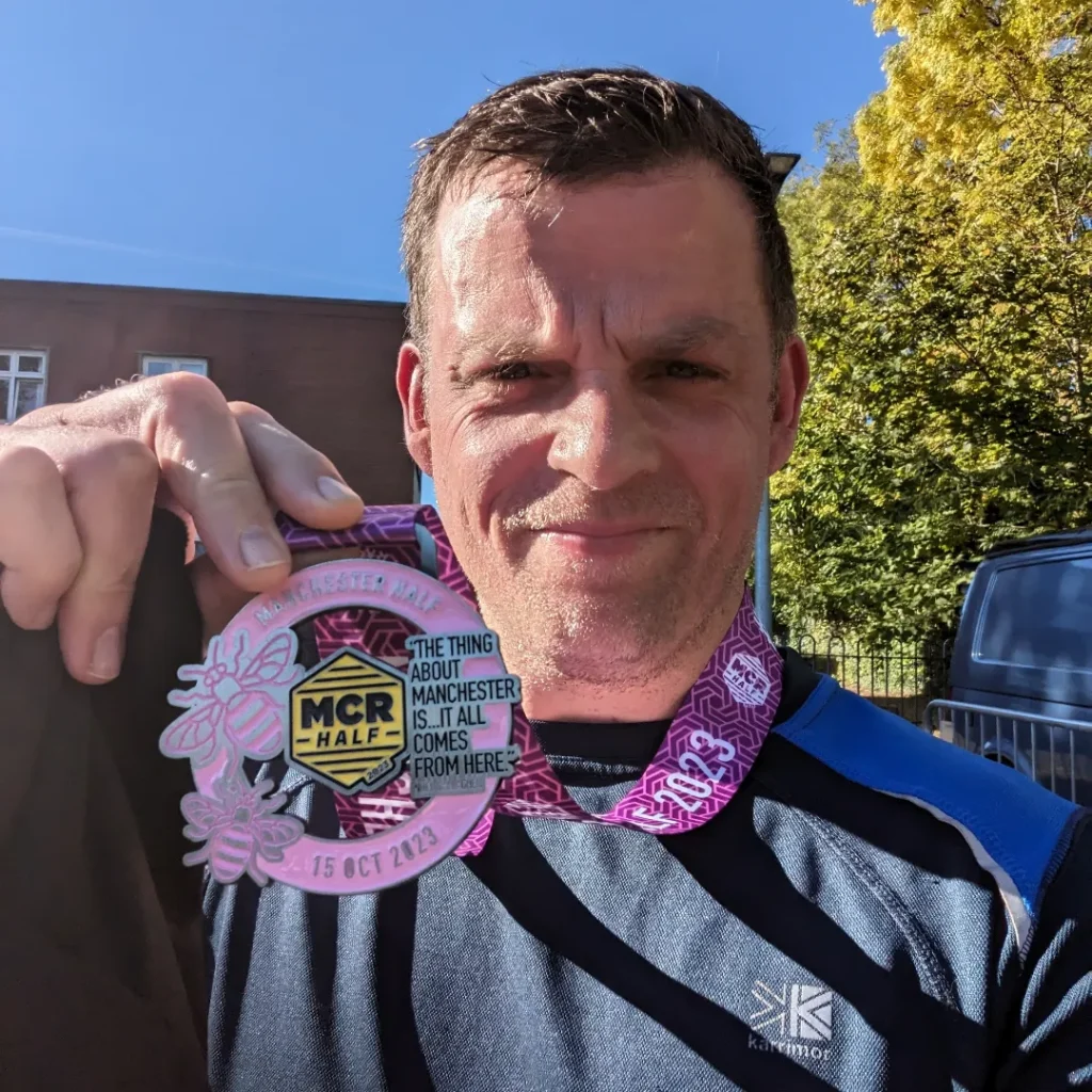 Me with my medal after running the Manchester half marathon in October 2023